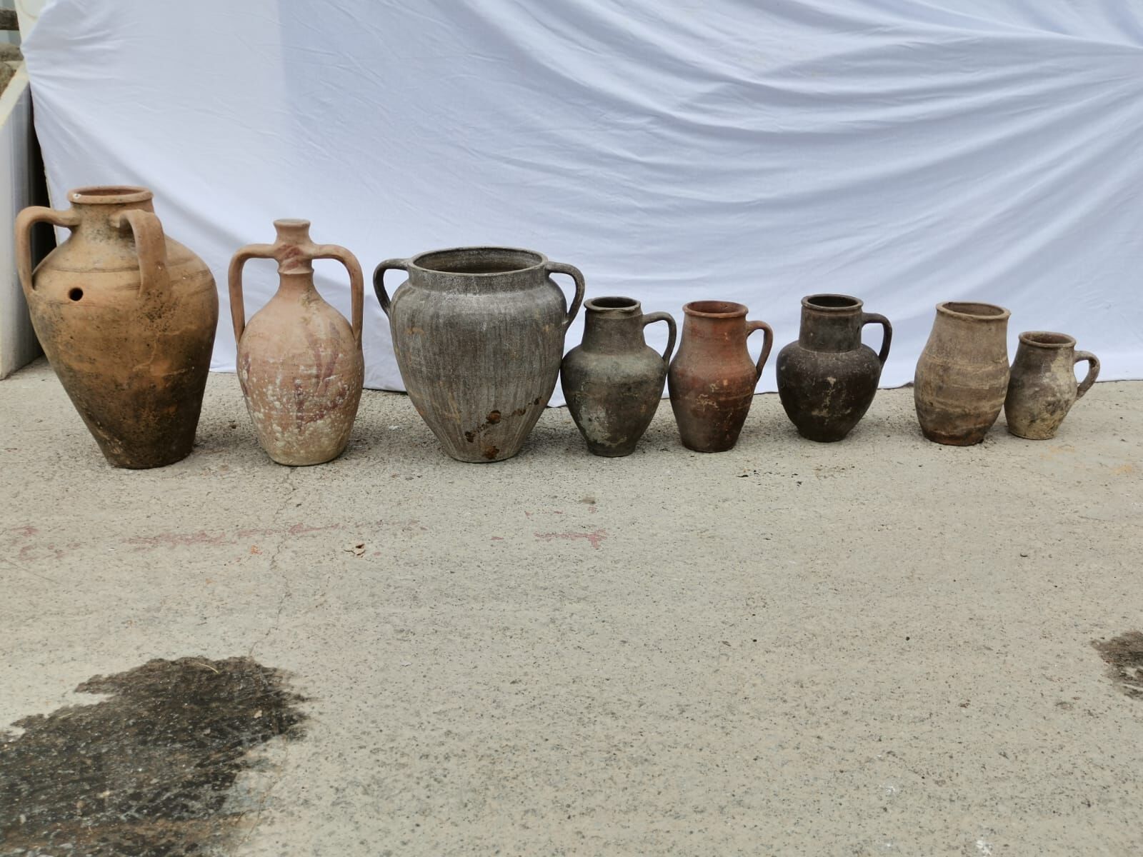Yoz Amphora, Small — row of small clay jugs in graded sizes on pale ground