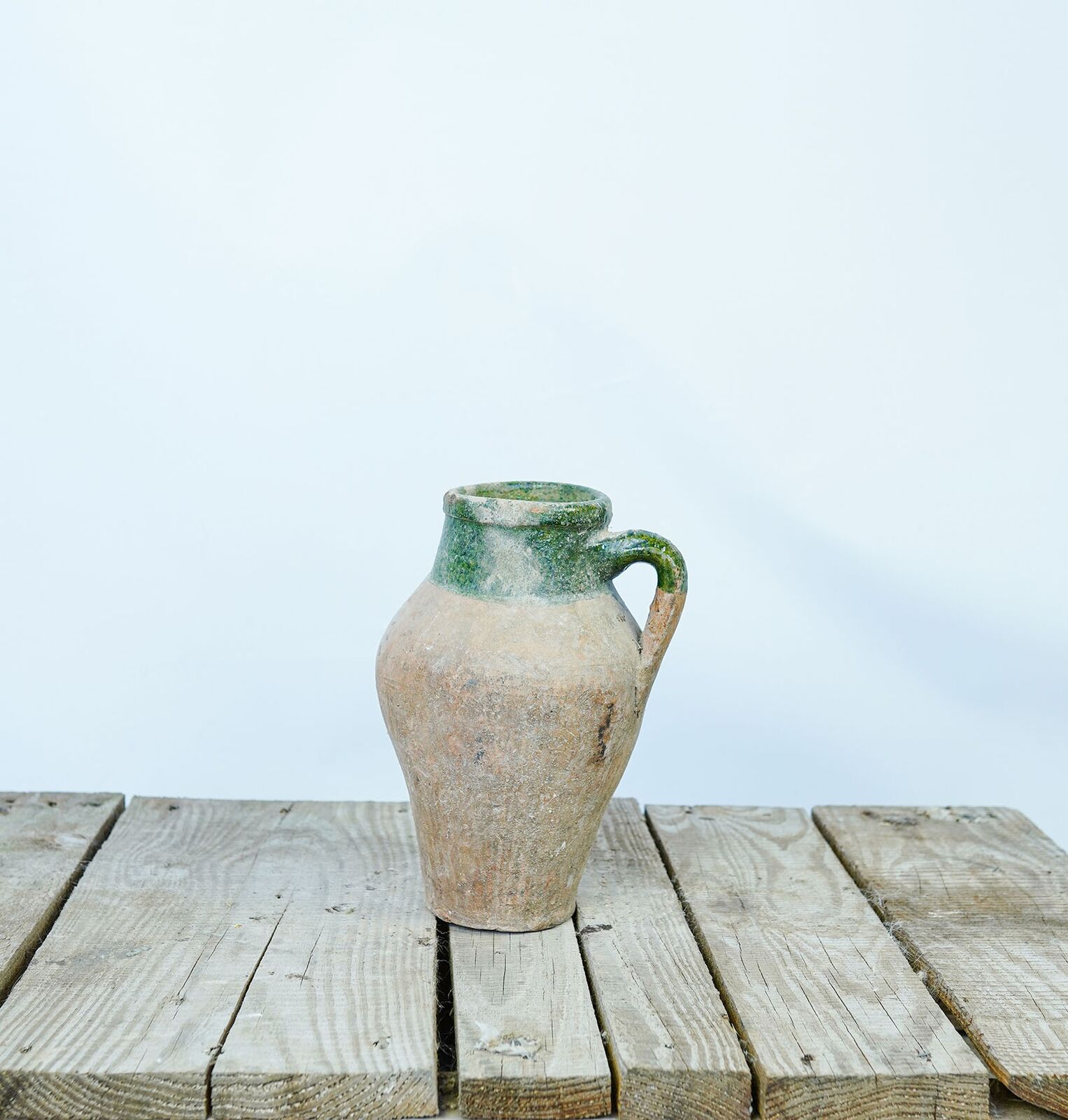 Konya Green Amphora, Large — weathered jar with a green-glazed handle and rim on a wooden pallet