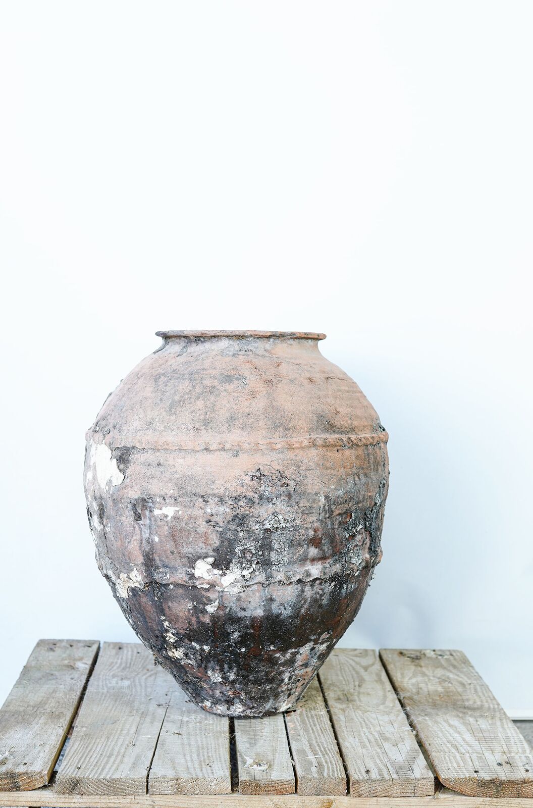 Belted Amphora — weathered grey-black belted jar on a wooden pallet