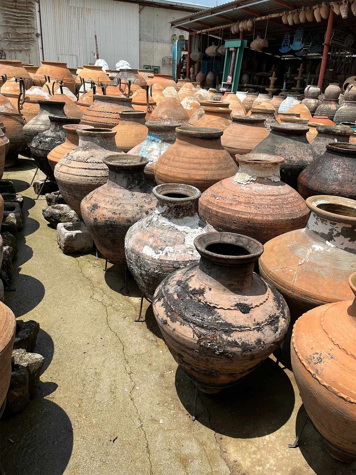 Enez Jar, Small — many round Enez jars in terracotta and charcoal on a gravel yard