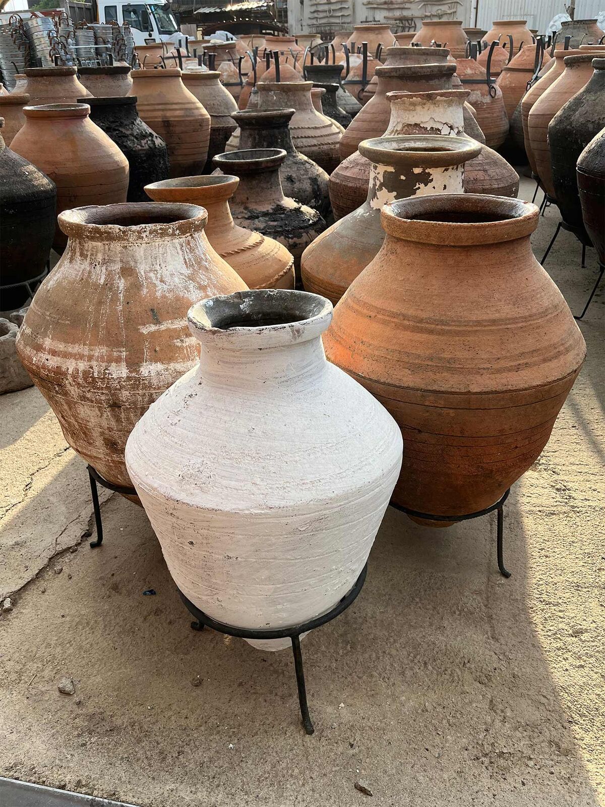 Enez Jar, Medium — terracotta Enez jars on iron stands beside a white-washed jar