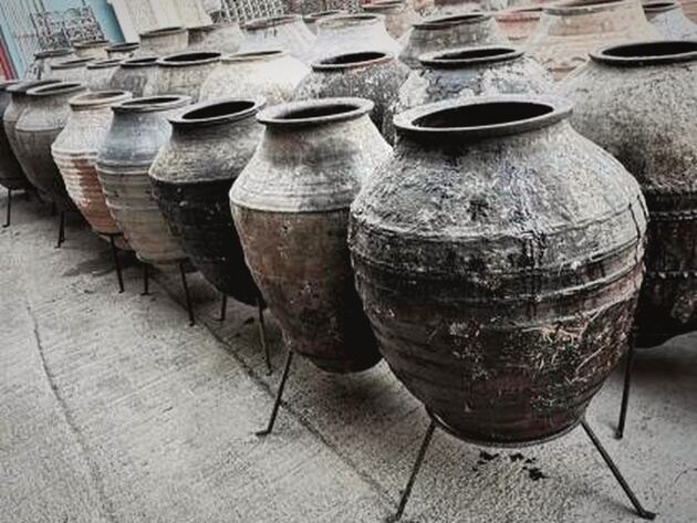 Enez Double Jar — rows of tall dark ribbed clay jars standing on iron stands