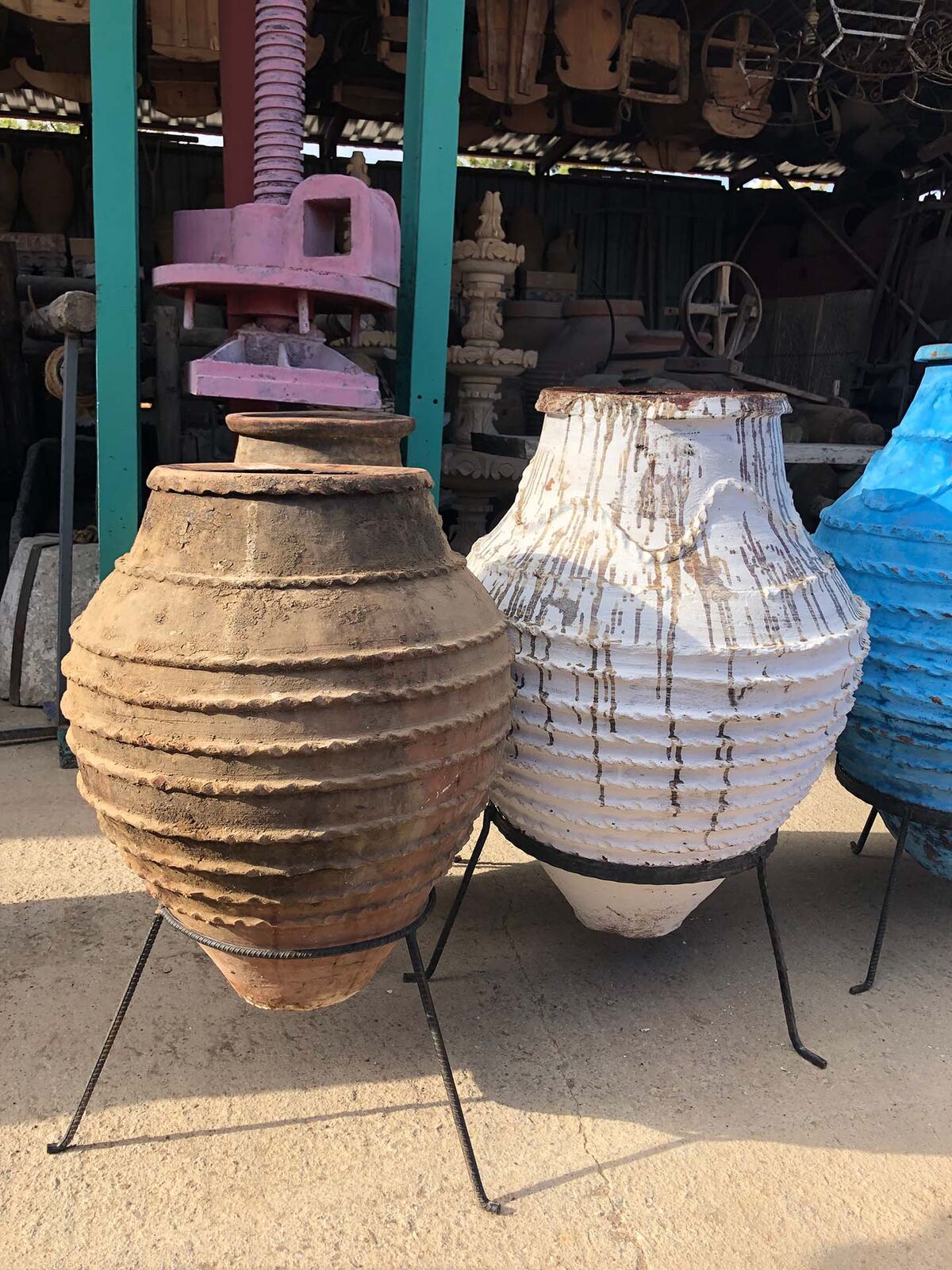 Monumental Oil Jar on Stand — large banded clay jar on an iron stand beside a white jar