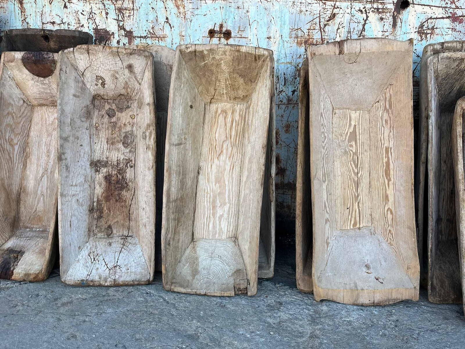 Wooden Trough, Square — row of long hollowed wooden troughs against a wall