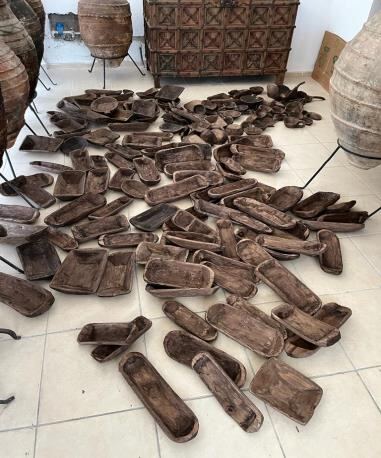 Many narrow boat-shaped wooden troughs in dark timber scattered across a tiled floor