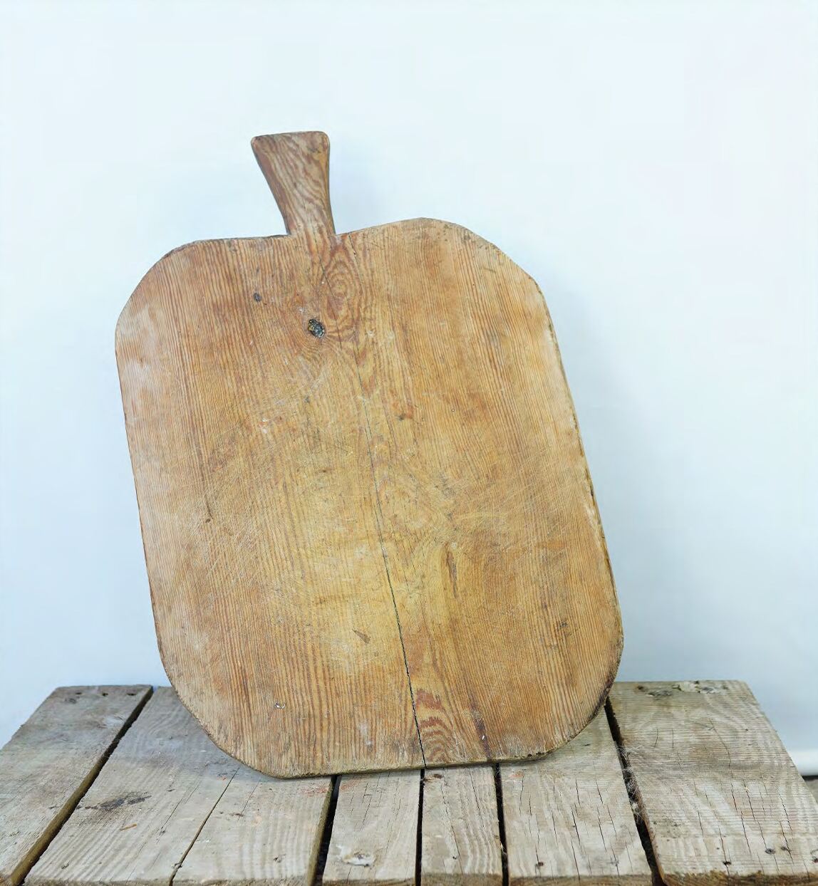 Paddle-shaped wooden bread board with a short handle on a plank floor