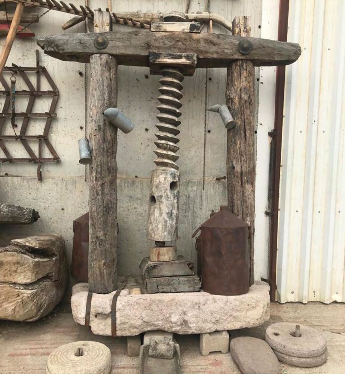 Wooden vertical screw press with a central threaded spindle inside a workshop
