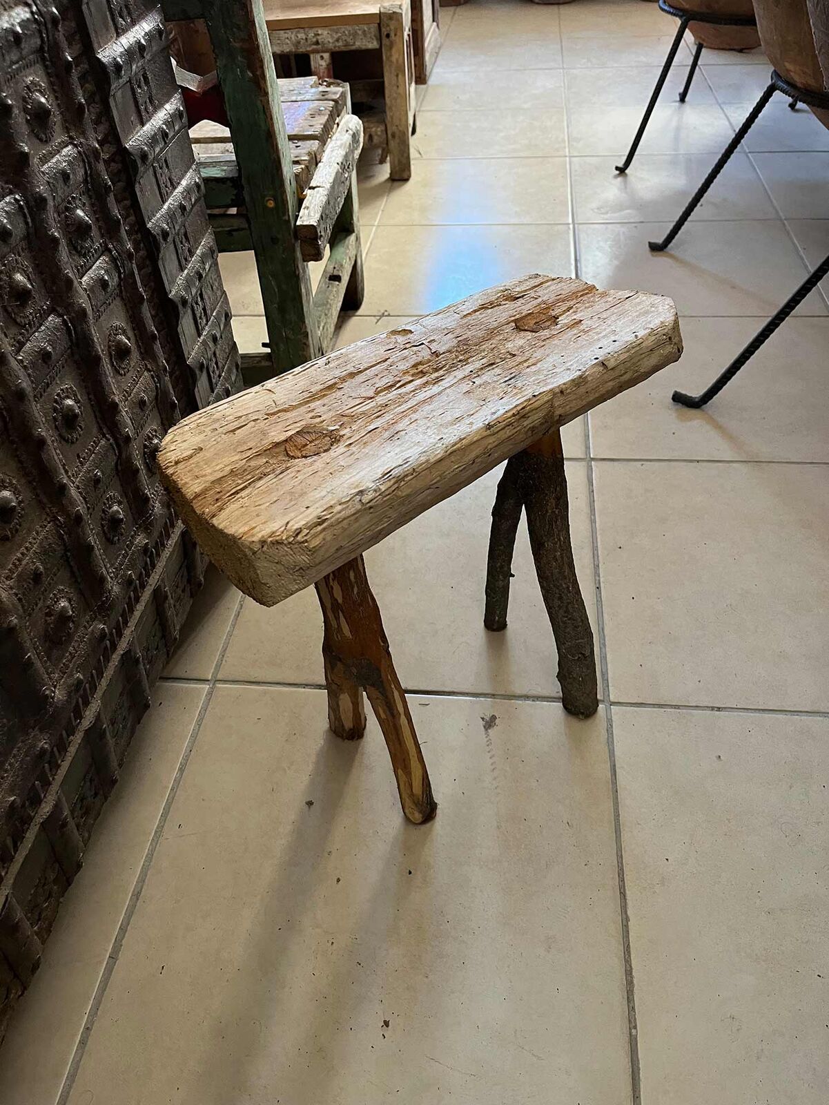 Hand-Hewn Wooden Stool — low wooden stool with a thick plank seat on a tiled floor