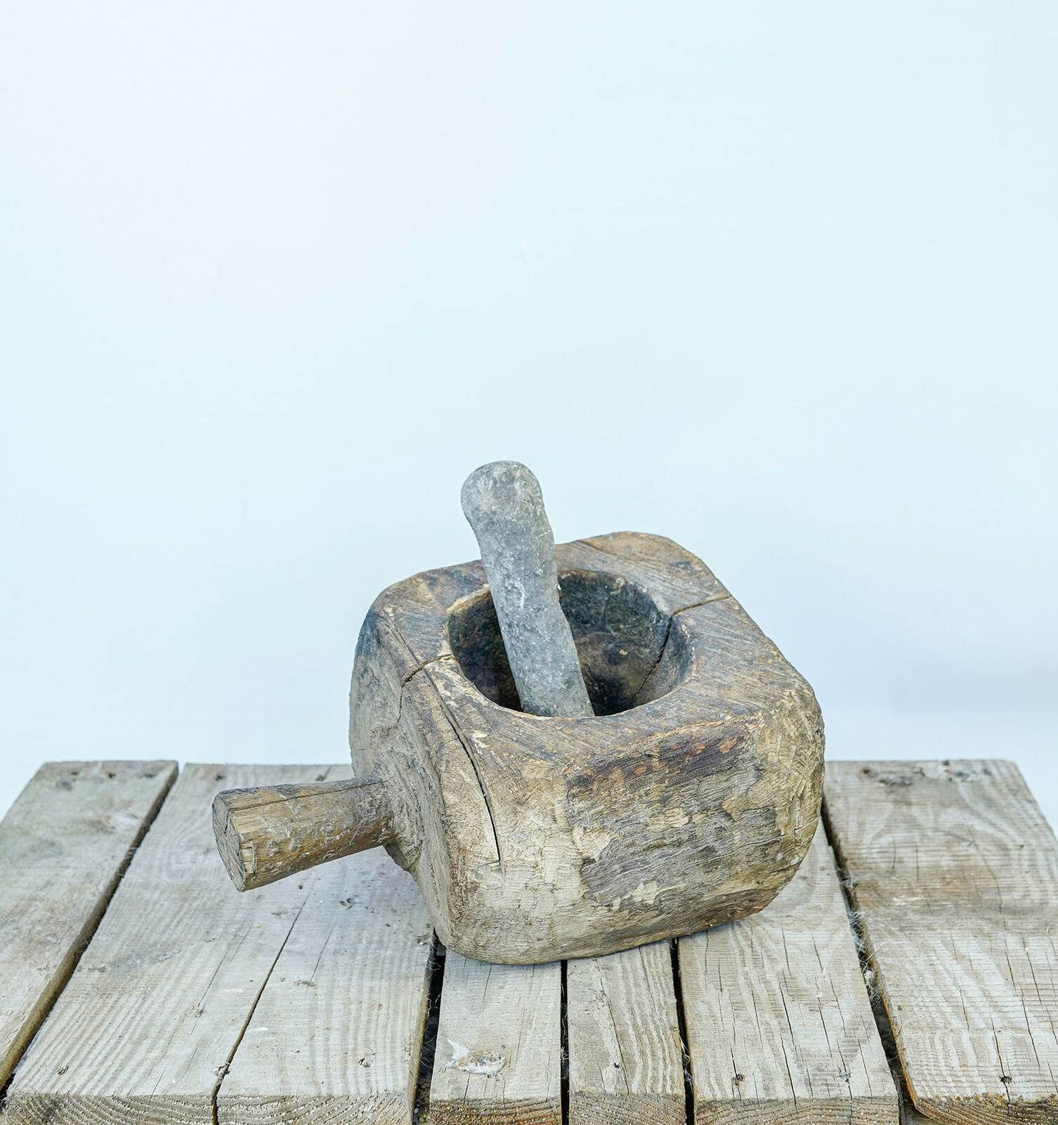 Wooden Mortar with Pestle — carved wooden mortar with a pestle and a side handle on a pallet