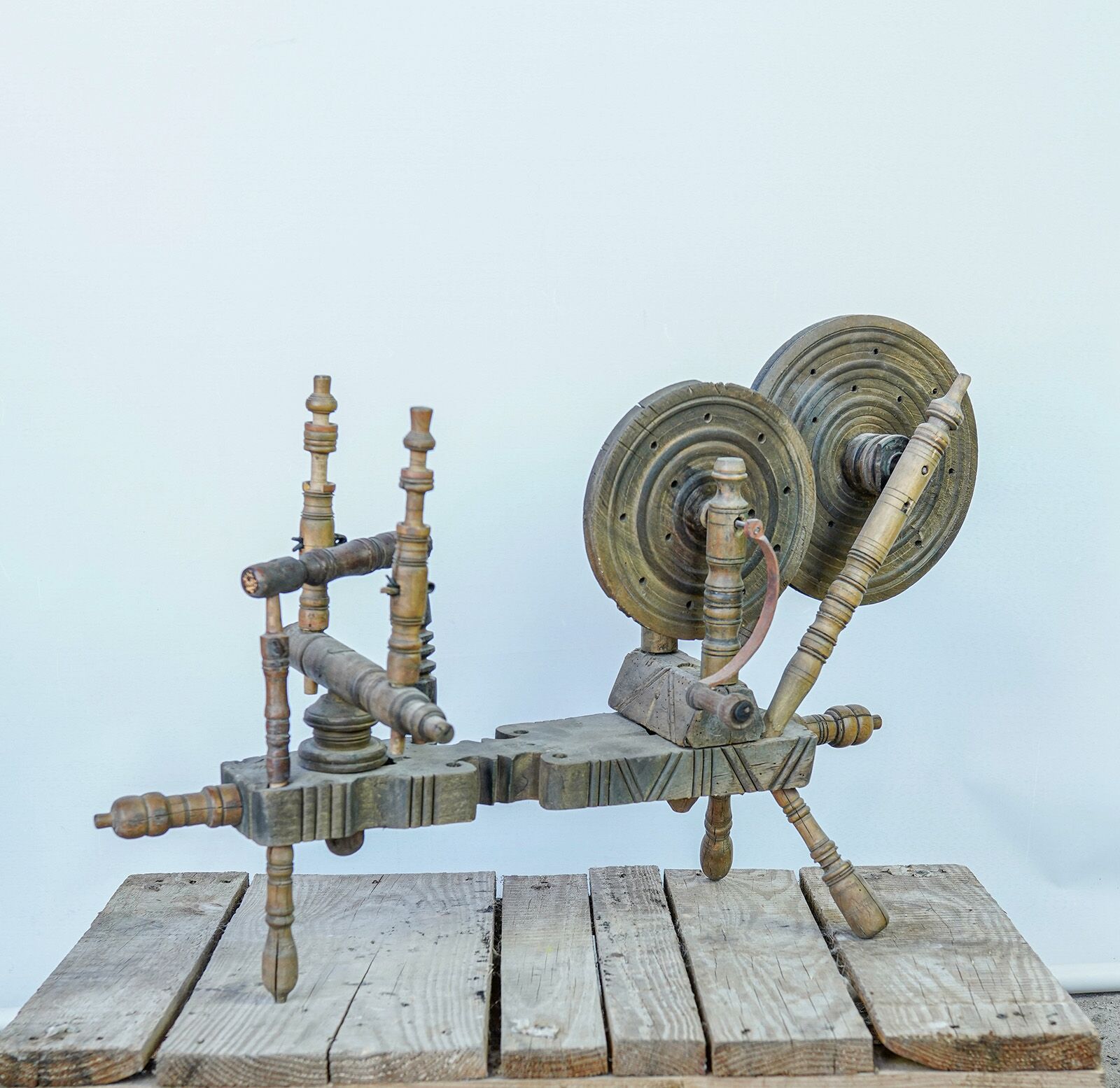 Wooden Spinning Wheel — wooden spinning wheel with turned spindles on a wooden pallet