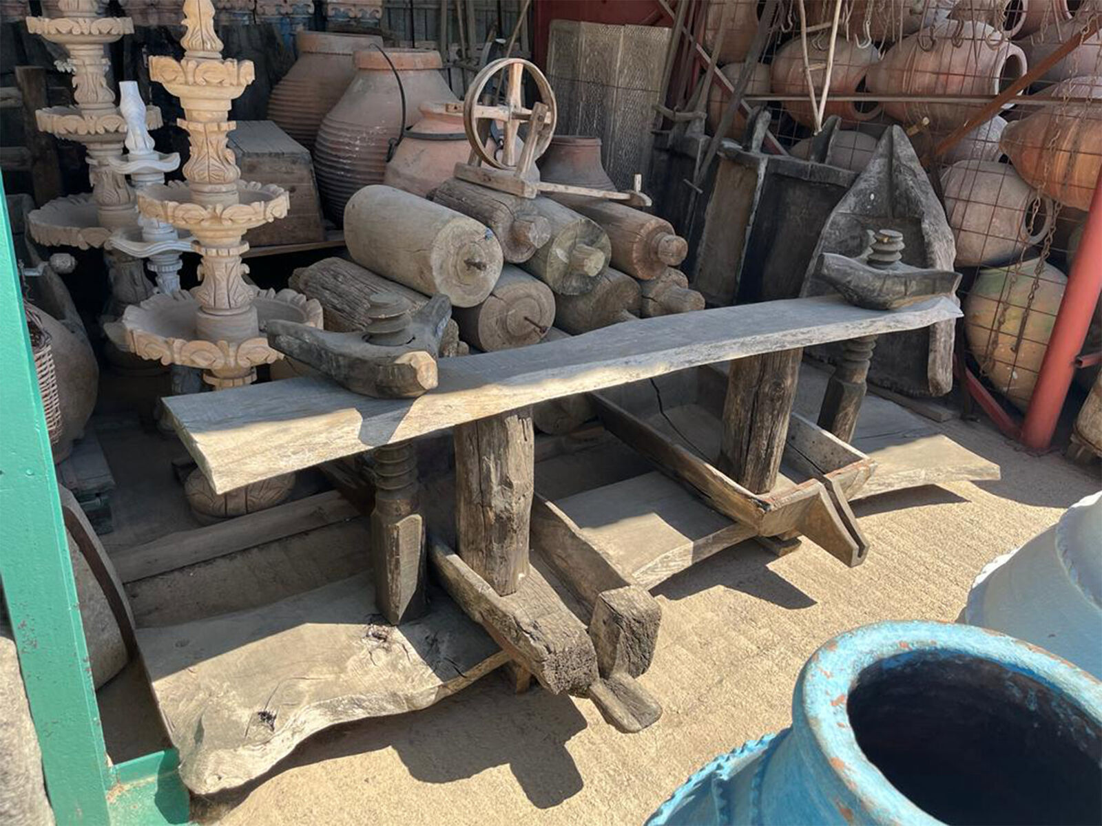 Wooden Spinning Frame — long wooden frame with spindles among stacked antiques