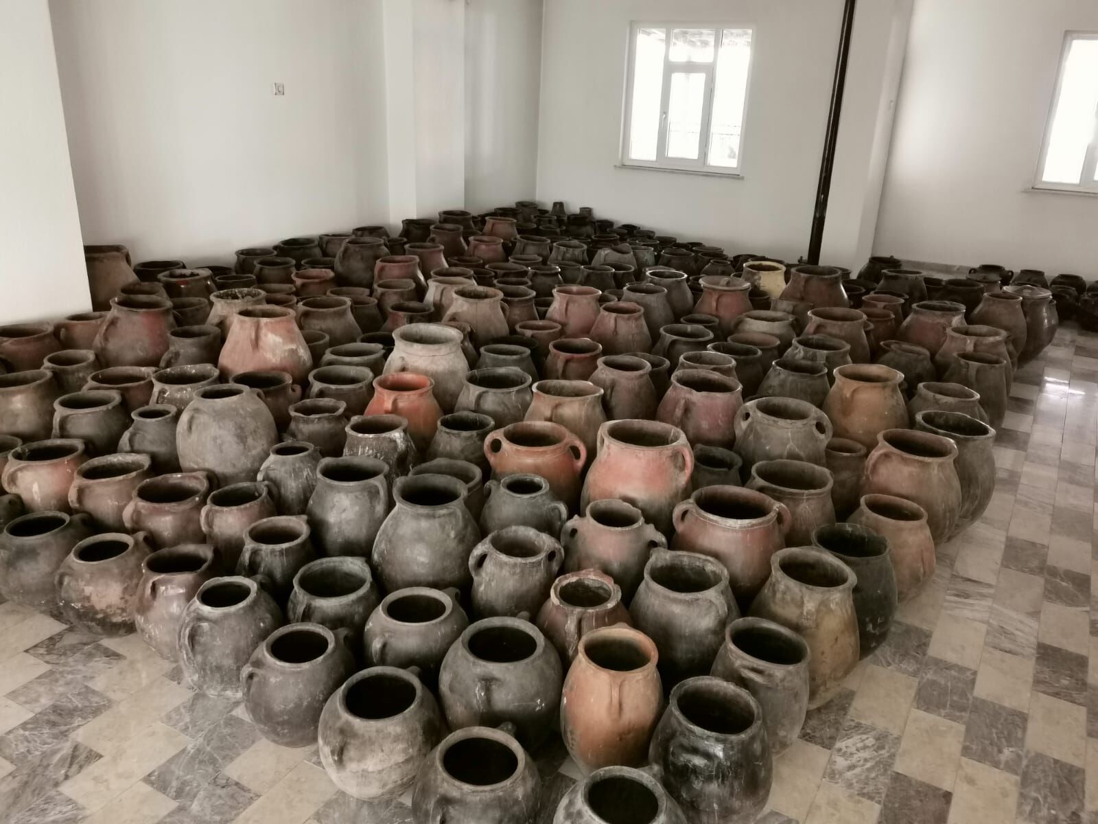 Erzurum Food Jar — rows of small black pots arranged on a tiled floor
