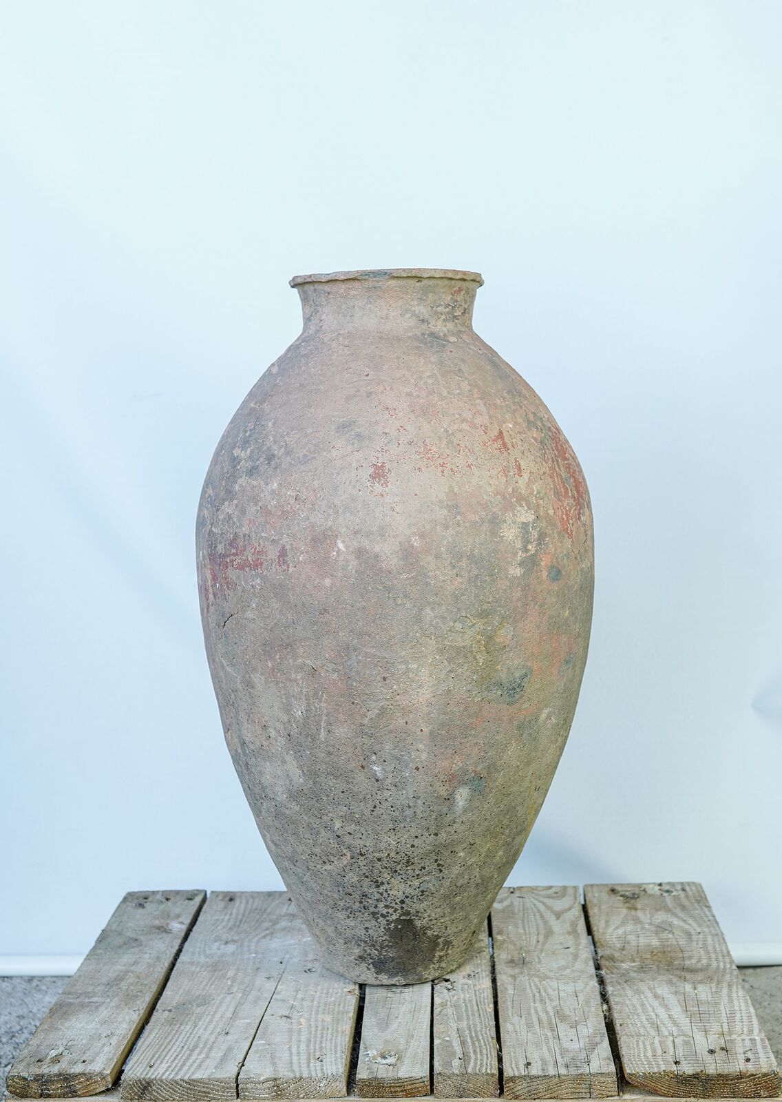 Eastern Handleless Jar, Tall — tall slender grey-brown clay jar without handles on a pallet