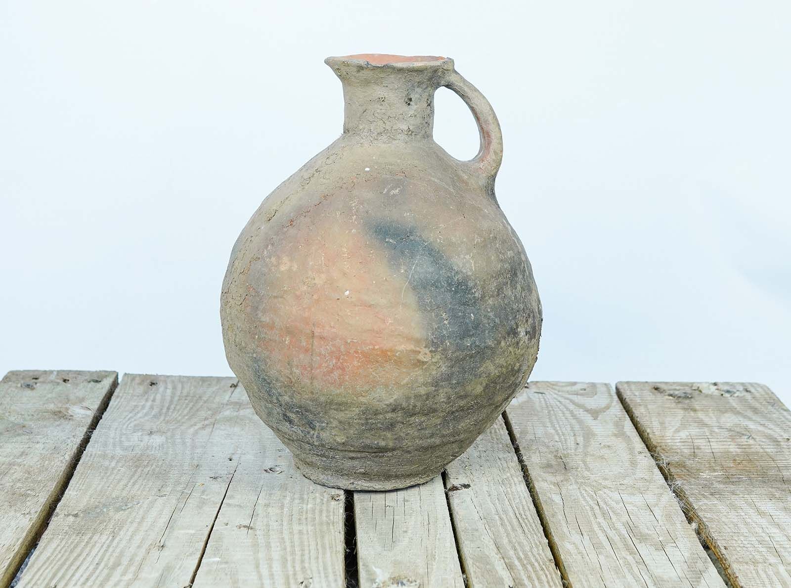 Eastern Single-Handled Jug — round clay jug with one handle in grey-brown on a wooden pallet