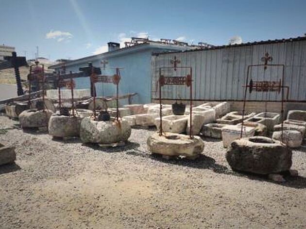 Antique Well Stone — carved stone well heads with iron frames in a gravel yard