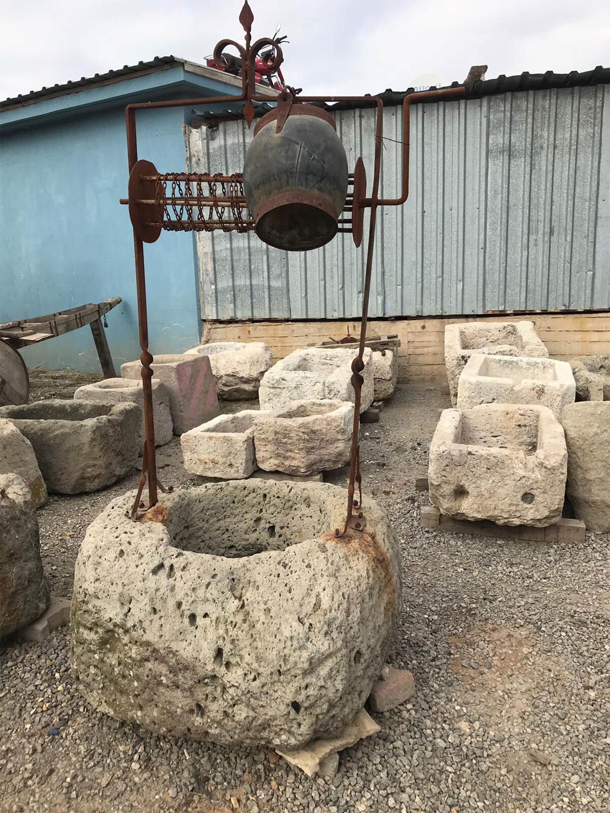 Antique Well Stone — old stone well head with an iron pulley frame above