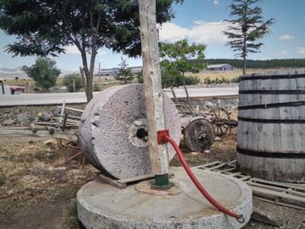 Olive Press Stone — large round stone millwheel on a stone base with a wooden post