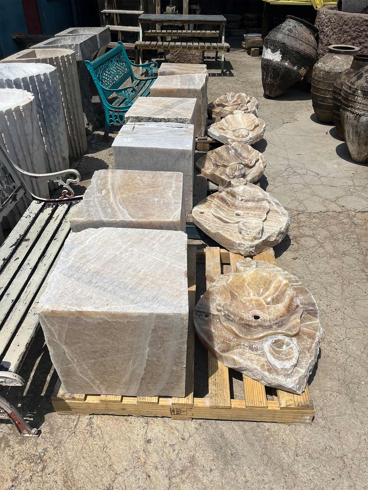 Onyx Marble Cubes and Sinks — blocks of veined onyx marble and shaped onyx sinks on pallets