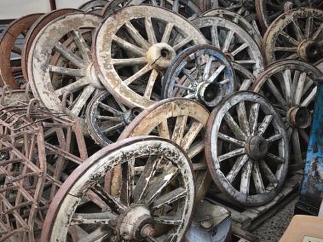 Antique Cart Wheel — pile of spoked wooden cart wheels with weathered paint and iron rims