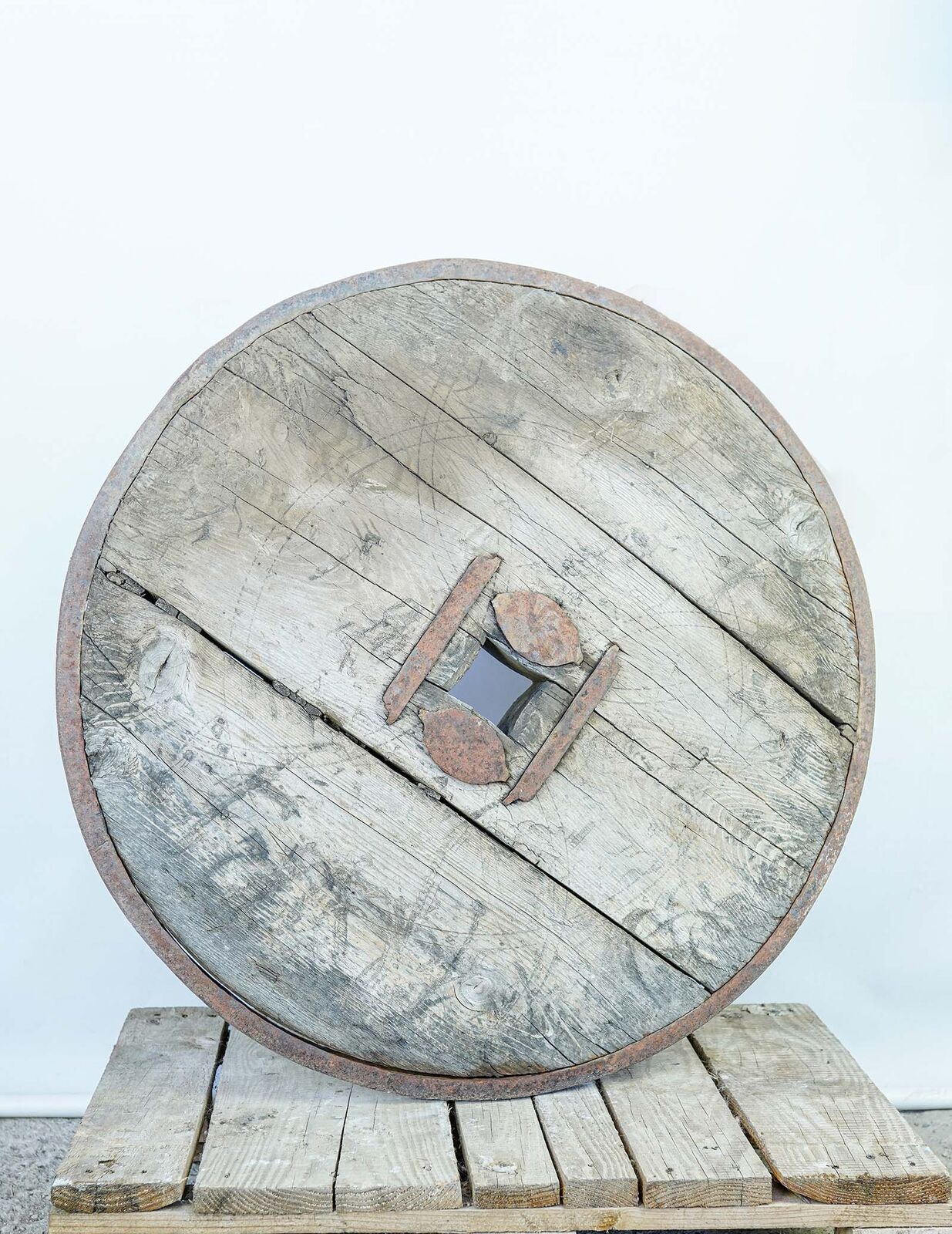 Solid Ox-Cart Wheel — large solid wooden cart wheel with an iron hub plate on a pallet