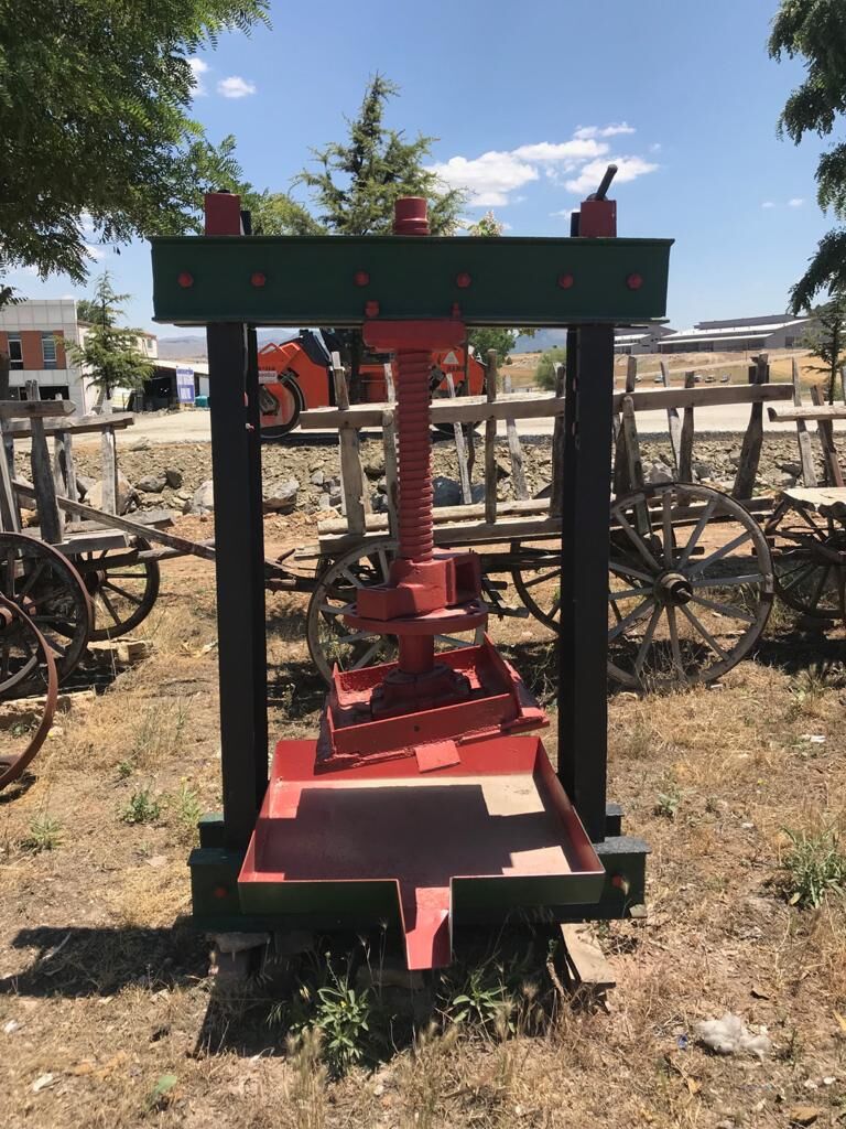 Red Iron Screw Press — iron screw press with a red frame and green uprights in a yard