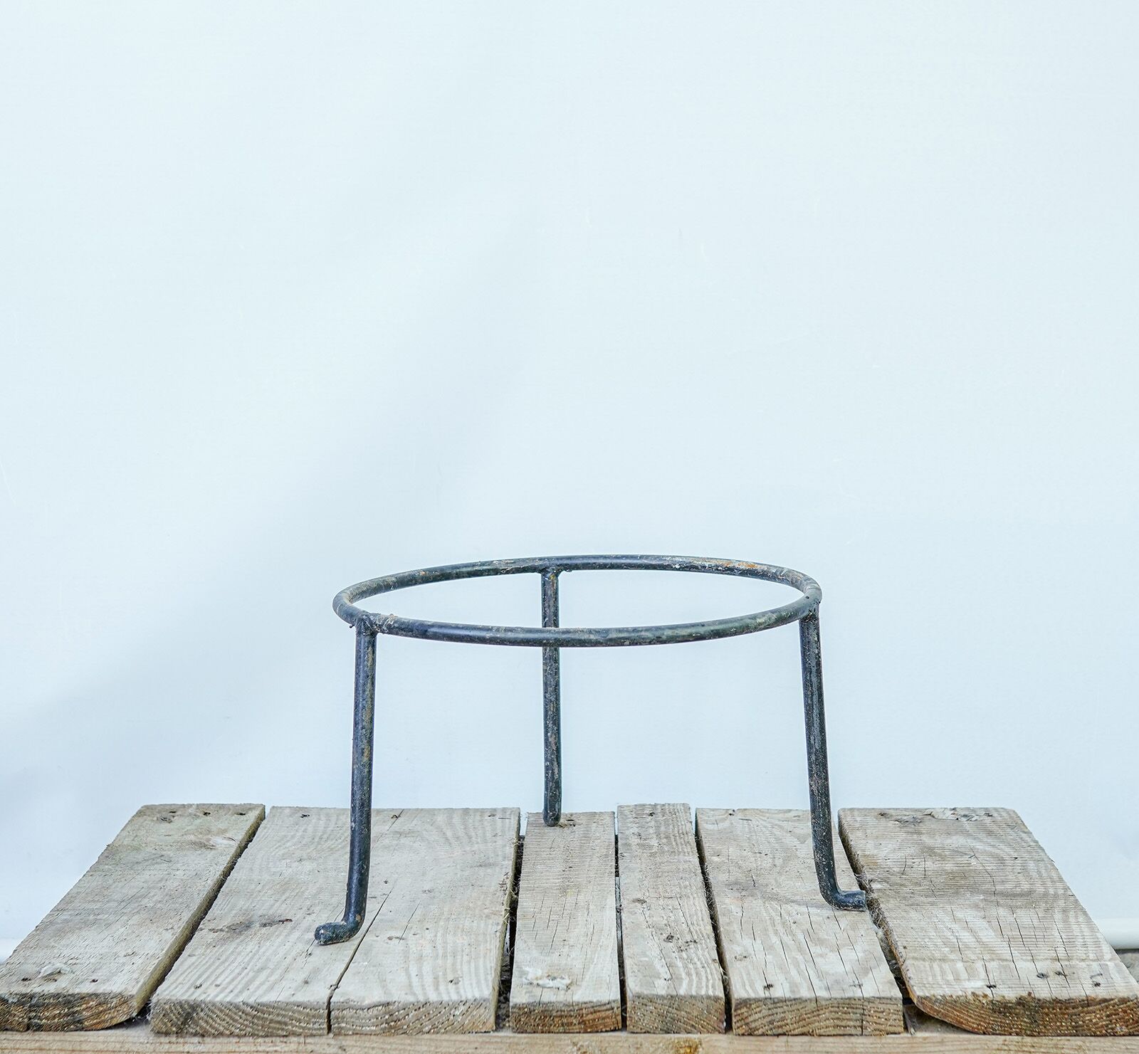 Wrought-Iron Jar Stand — black wrought-iron ring stand on three legs on a wooden pallet
