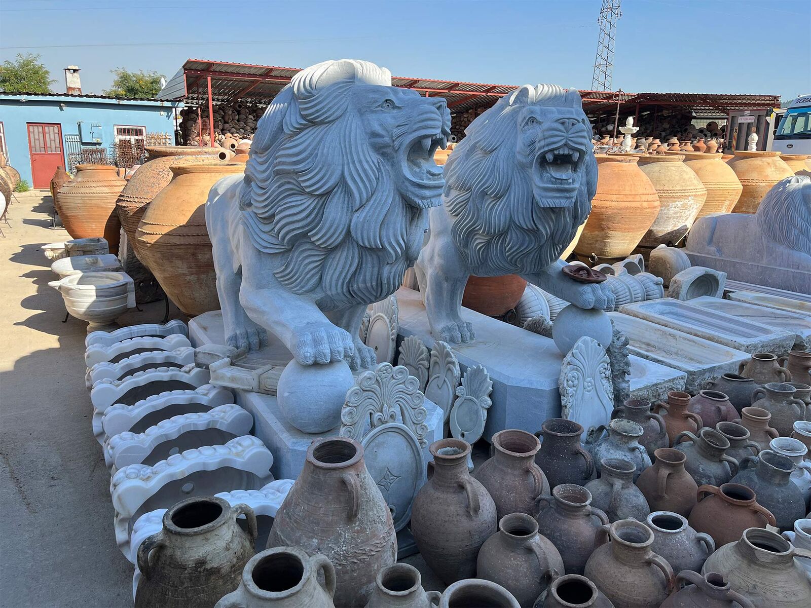 Marble Lion Statue — two white marble lions in a stone yard among clay jars