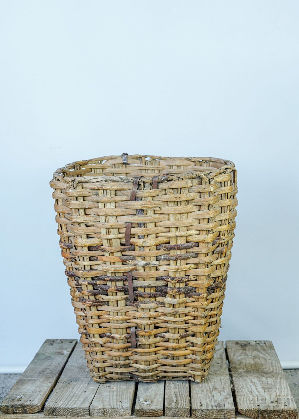 Woven Wicker Basket — tall woven wicker basket on a wooden pallet