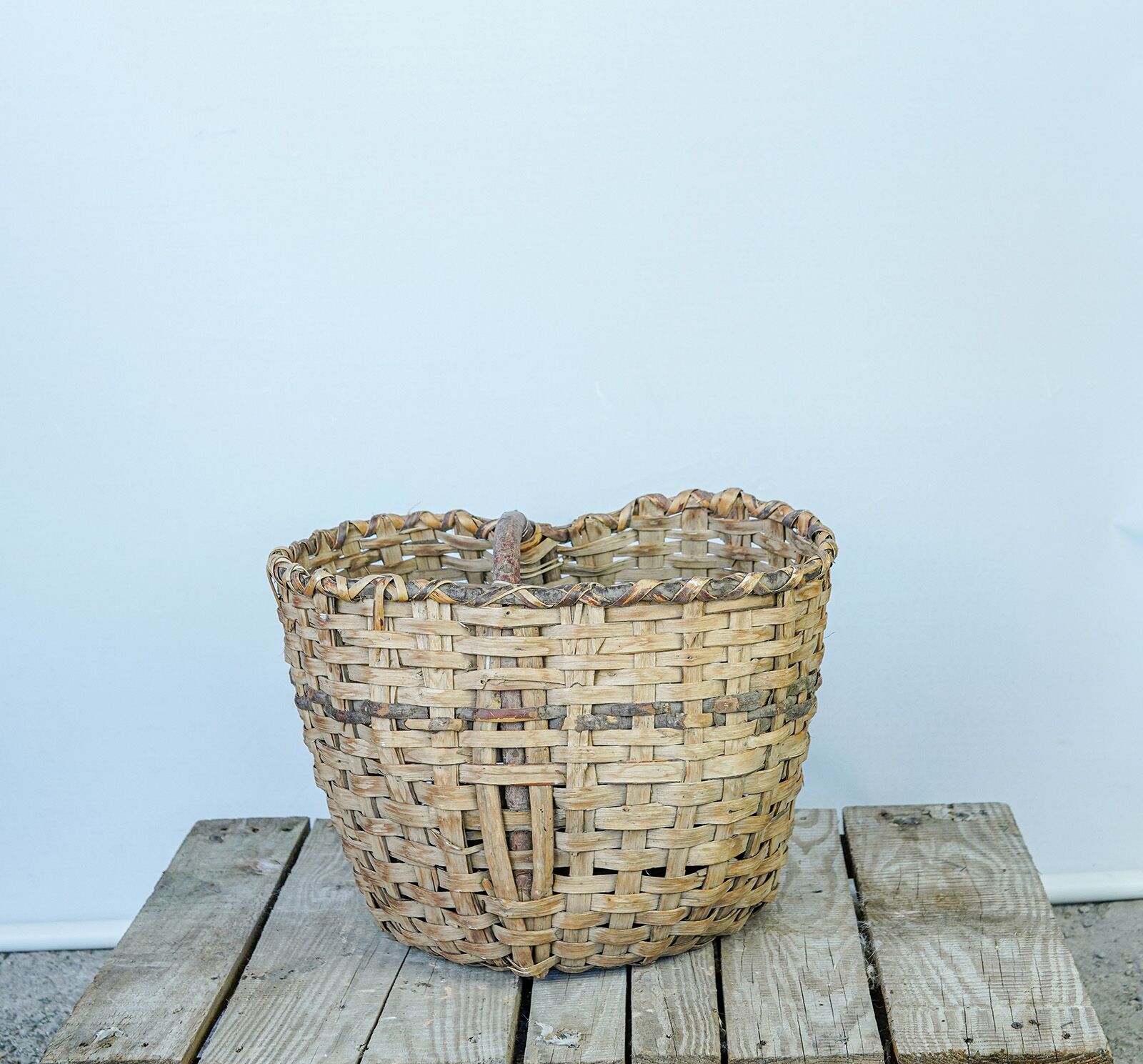 Woven Wicker Basket — wide woven wicker basket on a wooden pallet