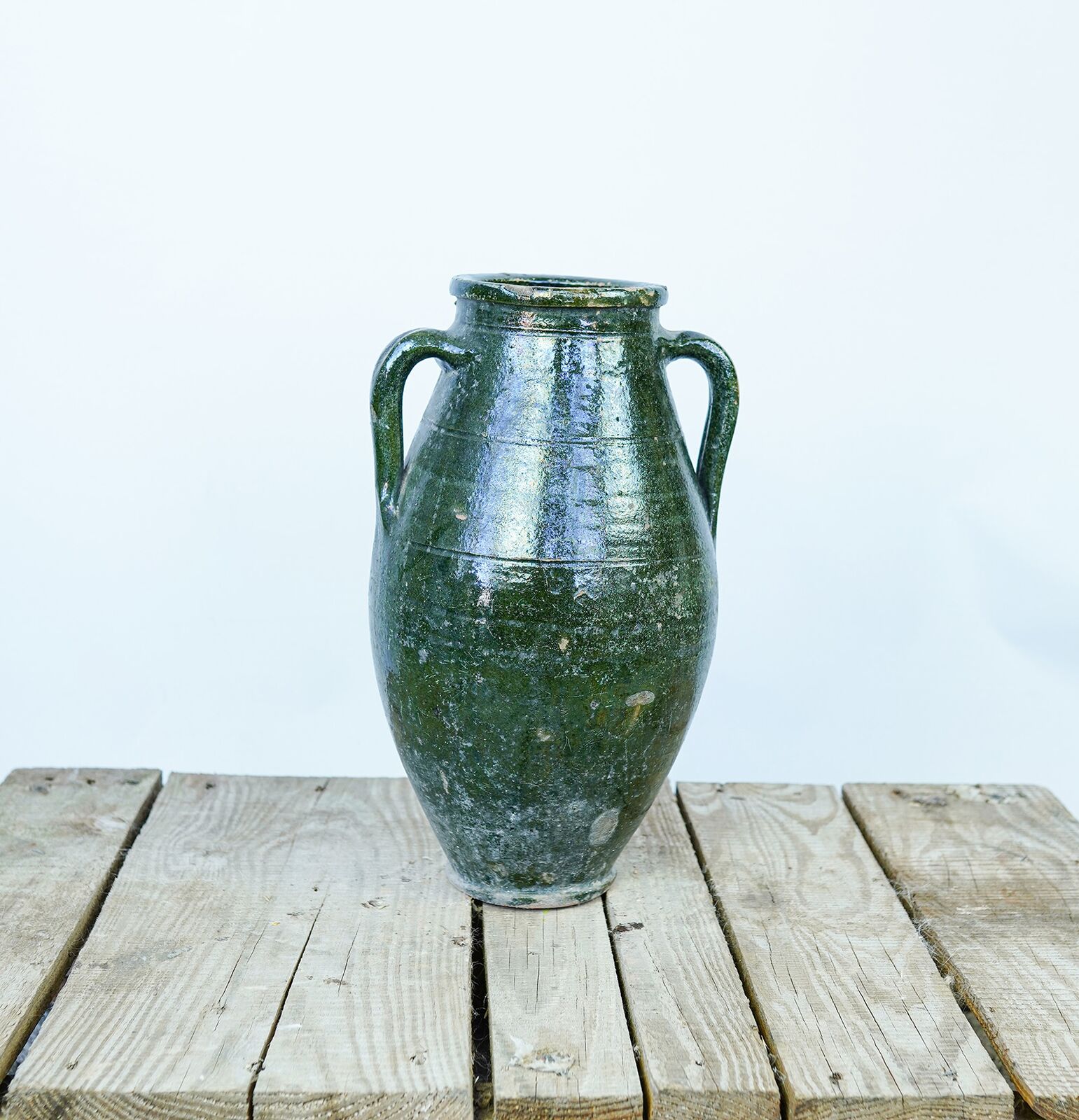 Antep Green Jar — dark green glazed two-handled jar on a wooden pallet