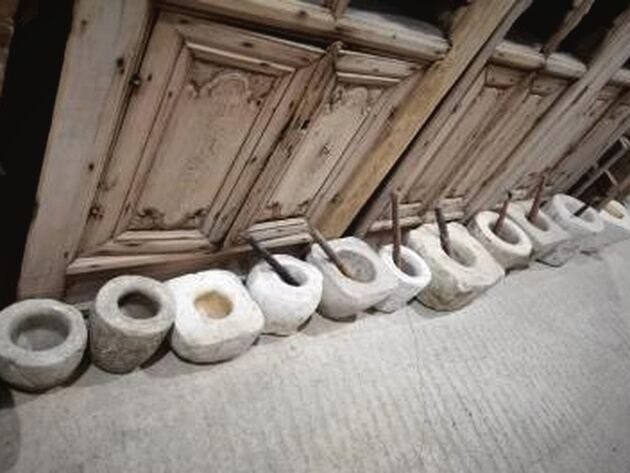 Stone Mortar — row of pale hand-cut stone mortars with wooden pestles