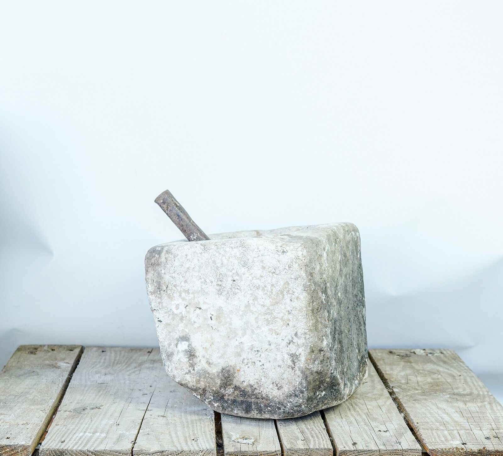 Stone Mortar — square stone mortar with a wooden pestle on a pallet