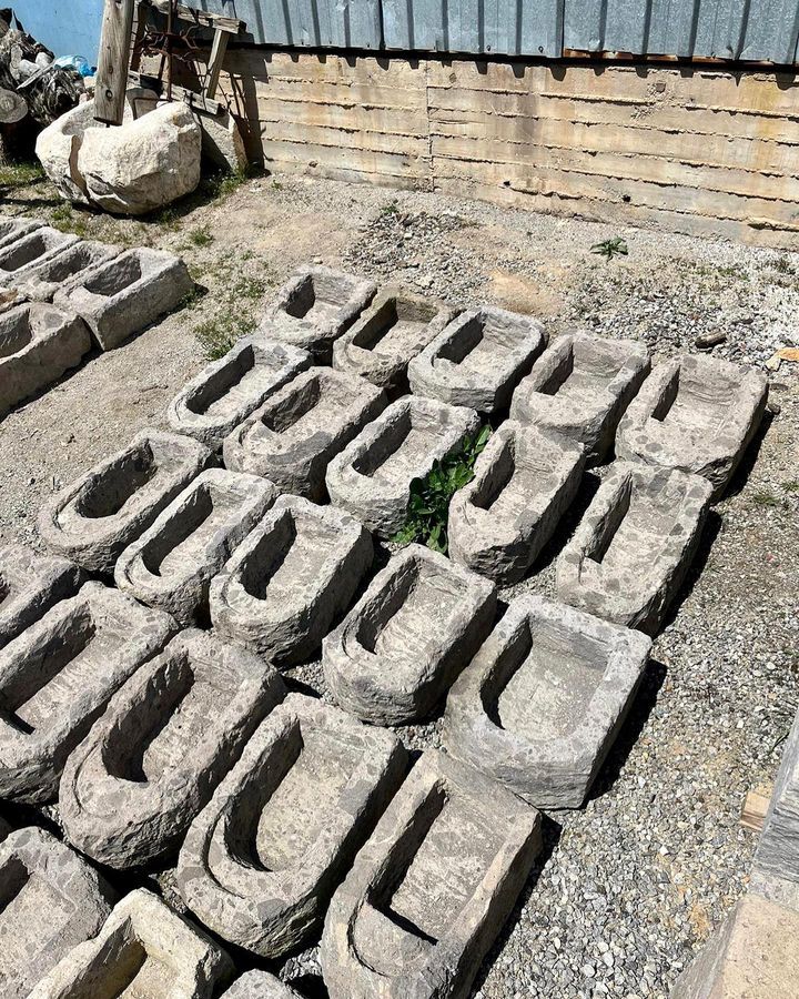 Stone Dibek Mortar — rows of carved stone mortars laid out on gravel