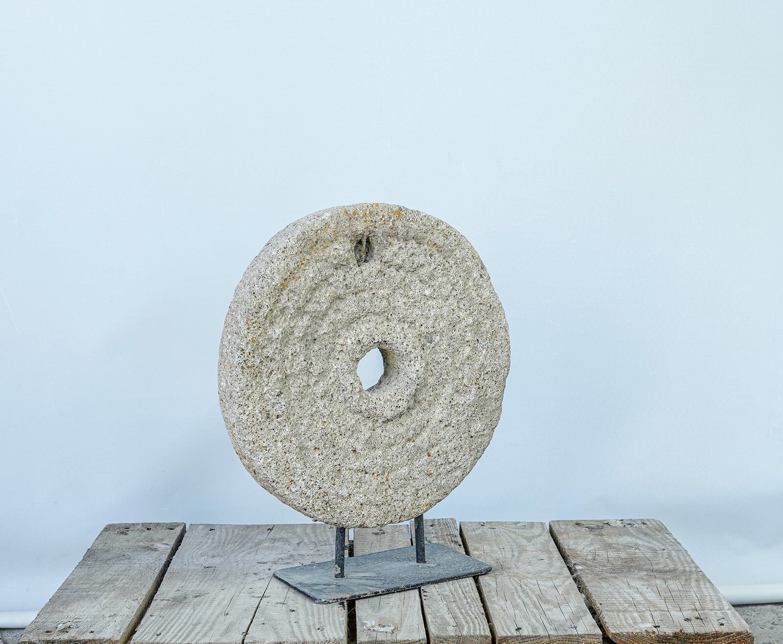 Lava Stone Wheel on Stand — round stone disc mounted upright on an iron stand