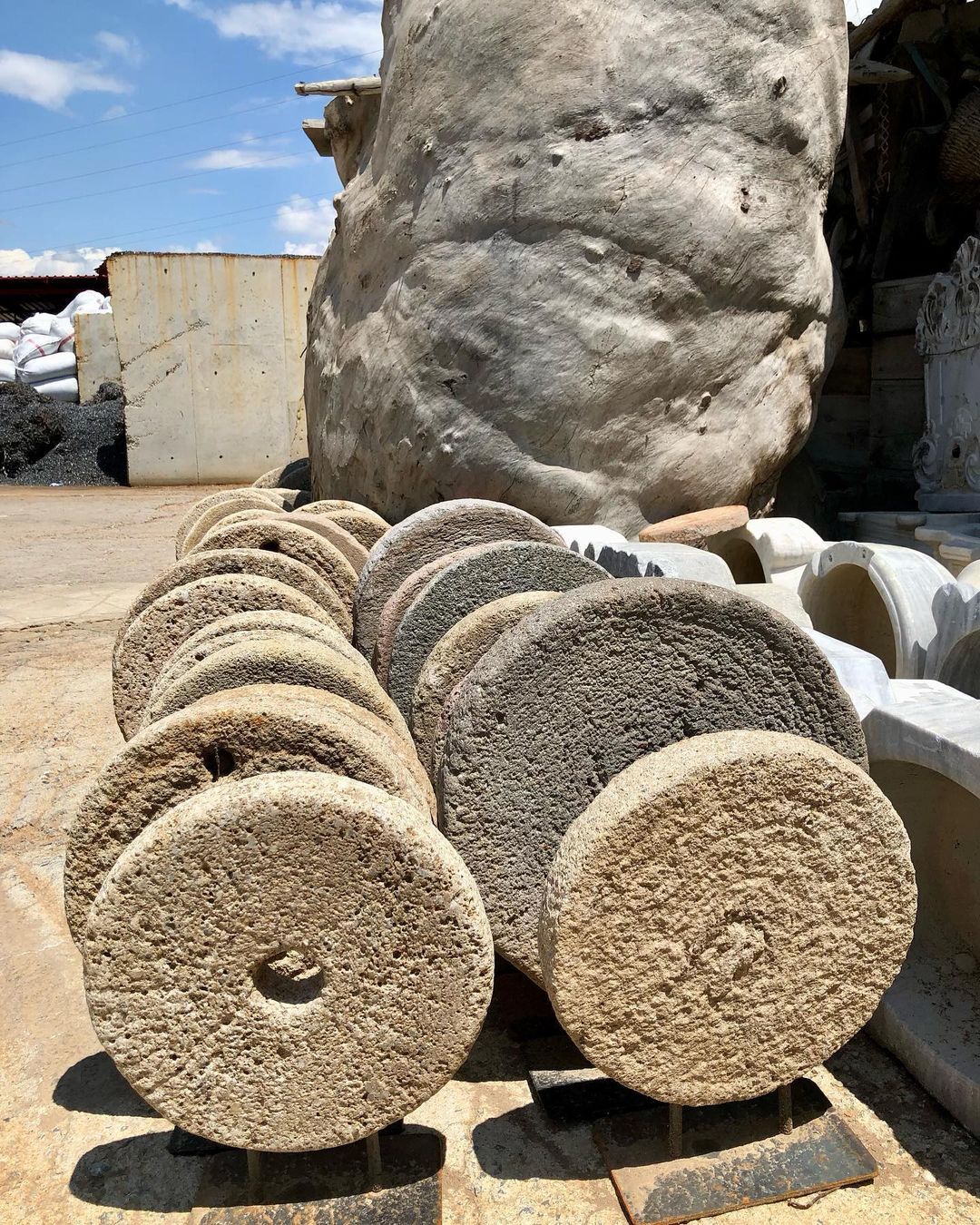 Lava Stone Wheel on Stand — pile of round stone mill wheels