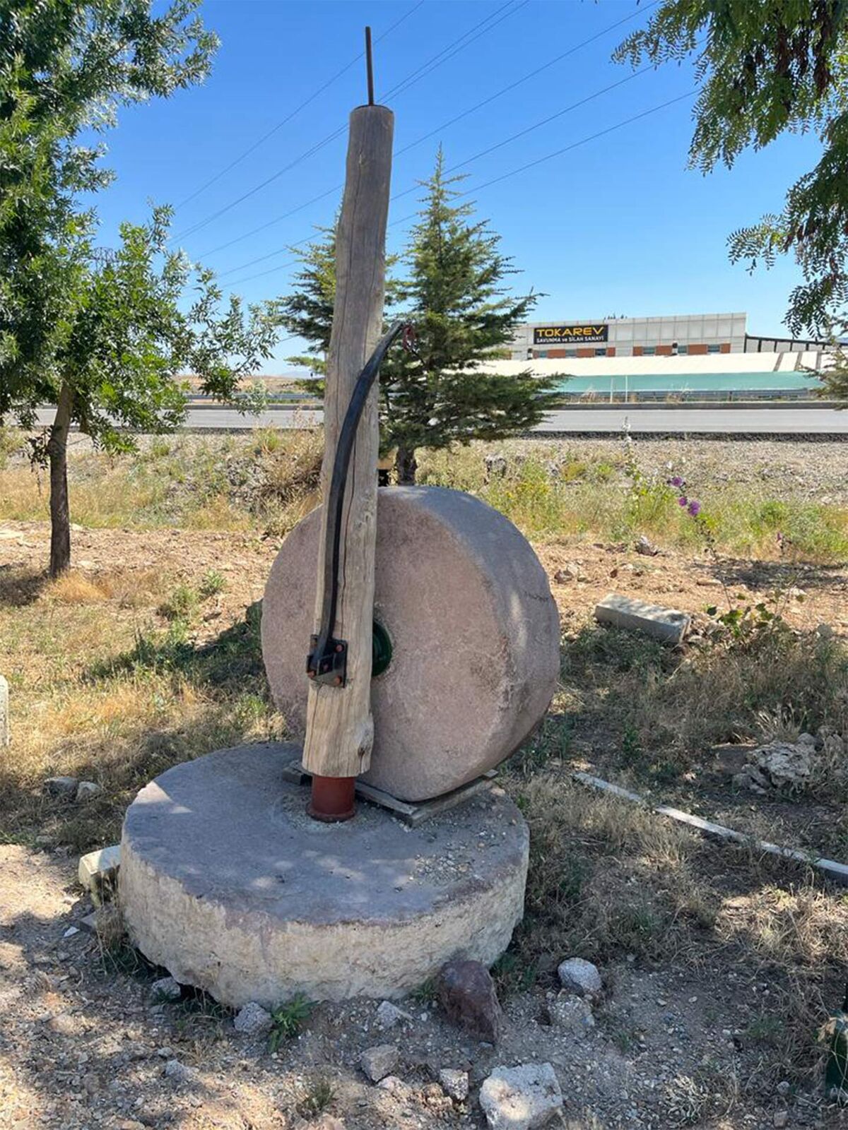 Stone Mill Set — upright millstone on a round stone base outdoors