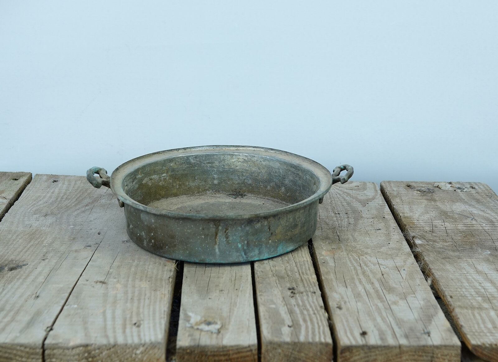 Copper Serving Pan — wide shallow copper pan with two handles on a wooden pallet
