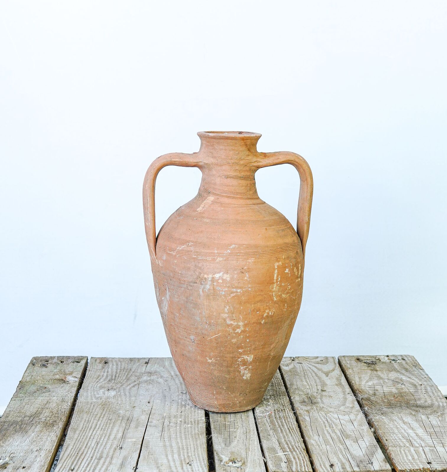 Amphora Jug — terracotta amphora jug with two handles on a wooden pallet
