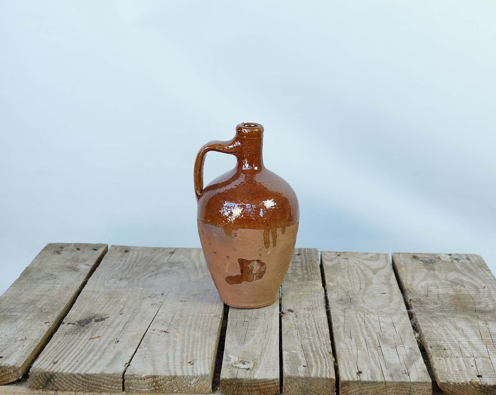 Konya Glazed Bottle Jug — amber and black glazed bottle jug with a handle on a pallet